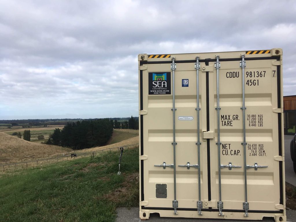 Beige shipping container with secure access in a rural setting.