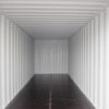 Interior of a white shipping container with wooden flooring.