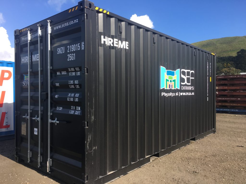 Black shipping container with secure access at storage yard.
