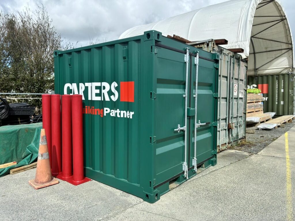 Small 8ft green shipping container branded with Carters, next to a container shelter