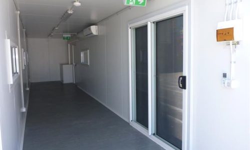 Interior of 40ft shipping container site office with sliding glass door and lined walls