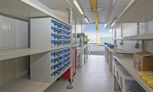Interior of modified shipping container workshop with shelving and drawers