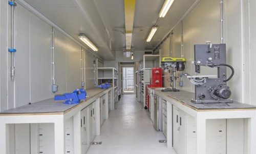Interior of container workshop with workbenches and drill press
