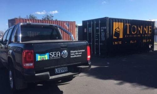 Black shipping container branded with Tonne Engineering Services, next to a SEA Containers ute
